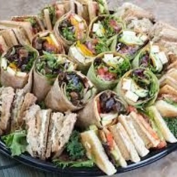 A catering platter filled with an assortment of cut sandwiches and wraps on a bed of lettuce.