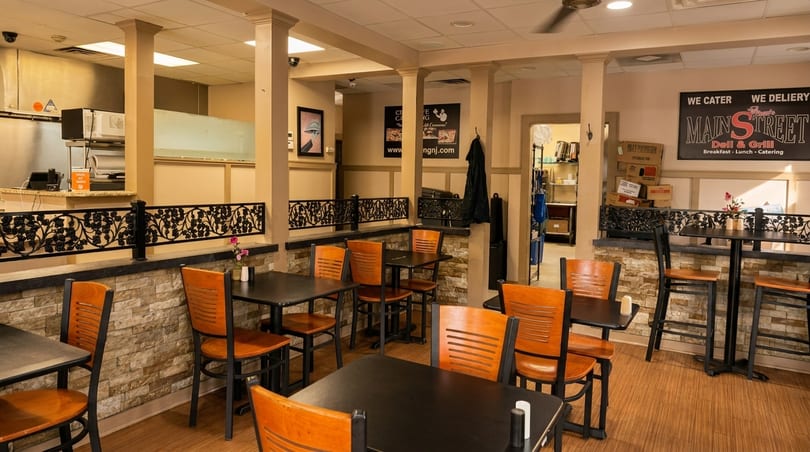 Interior of Main Street Deli & Grill with tables, chairs, and a counter area.
